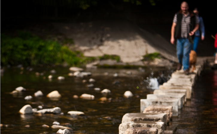 Man walking along stepping stones at Stanhope